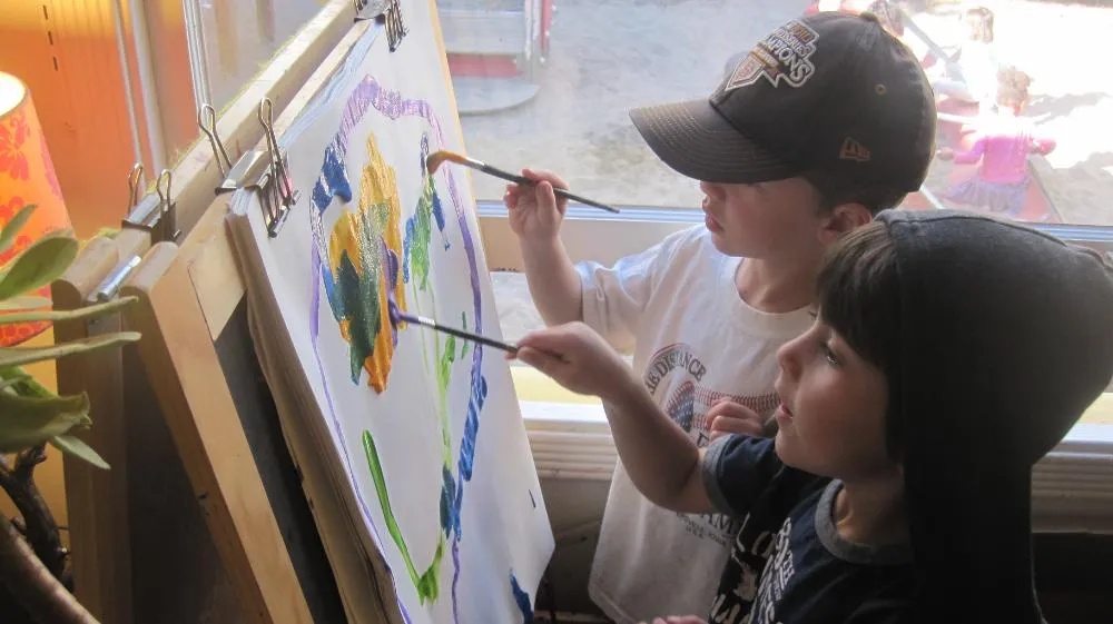 Two children painting at an easel