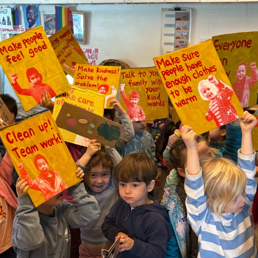 Children holding up hand-painted kindness signs in their classroom